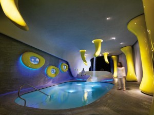 Dans le centre de bien-être,  des formes fluides définies en jaune  sortent de terre à différentes hauteurs,  d’autres, tachetées d’encastrés Pixel  Plus LED, descendent du plafond, le  perçant et emmenant avec elles des  cascades d’eau